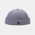 Close-up view of a minimalist blue-grey docker hat with black 'b.' letter embroidery - Adjustable / Blue