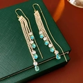 Detail of gold tassel earrings with water-drop blue gems on a green jewelry box - Tassel Ear Line Style / Gold with Blue