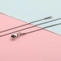 Dettaglio di una collana a catena box argento con chiusura a moschettone su sfondo bicolore - Color Acciaio