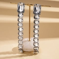 Macro view of crystal rhinestone rectangle drop earrings on golden T-bar display stand - Silver