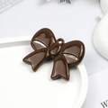 Detailed view of a brown glossy acrylic bow charm with a hanging hole on a white tray - Brown