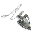 Macro shot of silver metal pendant featuring labradorite stone and carved skull details - Labradorite + Pendulum Chain