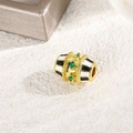 Dettaglio macro di perla ovale dorata con pietra verde e motivo a smalto bianco e nero - Bianco e Nero