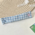 Dettaglio dell'organizzatore cavi in tessuto a quadretti blu con bottoni colorati - Quadri Blu Chiaro