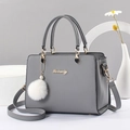 Chic grey tote bag with pompom charm and gold heart hardware on minimalist background - Dark Gray