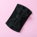 Detailed close-up of a black waffle knit baby headband with a large bow on pink background - Classic Black Bow (12)