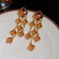 Détail des boucles d'oreilles trèfle ambré à pampilles sur une assiette en céramique - Bordure Dorée Ambre (Café)
