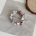 Dettaglio di uno scrunchie in seta con motivi floreali rosa e verdi su sfondo bianco - Bianco con Fiore