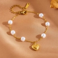 Golden stainless steel bracelet featuring white pearls and a heart pendant on silk background - Classic Heart Pearl Bracelet