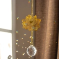 Golden lotus suncatcher with crystal prism reflecting rainbow light in a sunny window - Lotus Seed Pod Style
