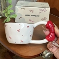 Ceramic mug with red bow handle and butterfly pattern held in hand - 300ml / Red