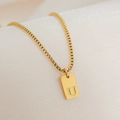 Macro detail of an 18K gold-plated box chain necklace with an engraved letter U square pendant - Letter U