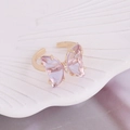 Macro detail of golden butterfly ring with faceted purple crystal on shell tray - One Size / Purple