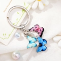 Detailed view of silver metal keychain with pink and blue enamel butterfly charms on fabric - Style 7 M745 (Pink/Light Blue/Dark Blue Butterfly)