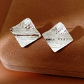 Detailaufnahme quadratischer Ohrstecker mit hämmerter Silberoberfläche und Textur - Silber mit Silbernadel (Echtvergoldet) / Silber