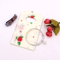 Silver bracelet with bell pendant resting on a rose patterned mini gift bag - No. 6 (Rose Pattern)