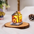 Detailed view of a glowing resin Christmas house with snow decor on a wooden base - Style A