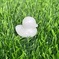 Close-up of a carved white crystal duck figurine placed on green artificial grass - White Jade