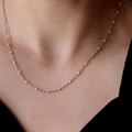Minimalistische 18k vergulde titanium ketting met kleine roze emaille kralen op de nek - Roze