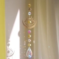 Golden evil eye suncatcher with yellow crystal prism creating rainbow light on wall - Yellow