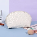 White Y2K heart embossed makeup bag with glossy finish and zipper closure on vanity desk - Shell / White