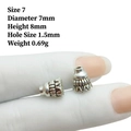 Detailed view of silver alloy flower spacer beads with embossed patterns on hand - 7# Silver (7x8mm)