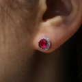 Macro close-up of a silver halo stud earring with a red gemstone and white zirconias - White Gold with Red Zircon