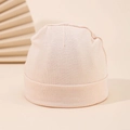 Nahaufnahme der weichen Baumwolltextur einer rosa Neugeborenen-Wintermütze für Babys - 0-3M / Beige