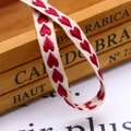 Macro shot of 10mm beige cotton ribbon with red heart embroidery for gift wrapping - 10mm / Red