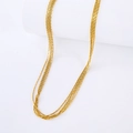 Detail of layered gold stainless steel necklace draped on a white cylindrical stand - Gold Necklace