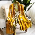 Elegant ginger yellow silk shawl with white floral print draped on a beige sofa - 90*180cm / Ginger Yellow