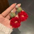 Dettaglio di orecchini a fiore in maglia rossa con perle e trama di filato intrecciato - Rosso