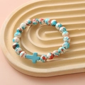 Close-up of beaded bracelet with blue, orange, white stones and a blue cross pendant - Blue Orange White Spotted Blue Cross Bracelet