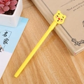 Cute yellow cartoon bear gel pen with decorative cap on a wooden desk with stationery - Red Nose Bear Yellow