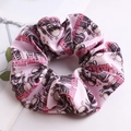 Close-up of pink oversized scrunchie with Valentine Club text and skull patterns - Pink