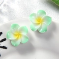 Detail of two resin plumeria flower hair clips with green gradient petals on a white plate - Small Green