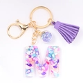 Detail of letter M resin keychain with colorful stones, purple tassel and gold hardware - Letter M