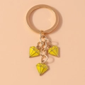 Dettaglio di un portachiavi dorato con tre ciondoli in smalto giallo a forma di diamante - Giallo
