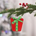 Red felt gift bag Christmas ornament with green bow and golden tree on a pine branch - Christmas Gift Box