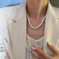 Elegante collana di perle tonde bianche indossata con un outfit in seta minimalista - Stile Grande Perla Gradiente Oro