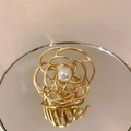 Detalle de una pinza para el pelo floral dorada con perla sobre una superficie de espejo - Dorado Grande