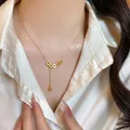 Elegant gold bow pendant necklace with cascading tassel and zircon detail on female model - Chinese Lucky Coin Necklace (X1774) / Gold/Coin
