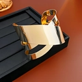Macro shot of an irregular gold twisted metal bangle on a black jewelry display stand - Three-layer Twisted Style (Gold)