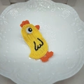Detailaufnahme der handgestrickten gelben Kükenspange mit orangefarbenem Kamm und Füßen - Huhn