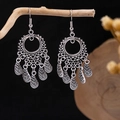 Detail view of vintage silver tassel earrings with ethnic leaf charms hanging on wood - Retro Hollow Ring Leaf Tassel Style (E2871-18)