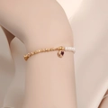 Gold chain pearl bracelet with a dark red heart pendant on a woman's wrist - Crushed Gold Heart Pearl Bracelet