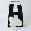 Detailed close-up of knitted bag texture with white flower pattern on black background - Black White Four Petal Flower