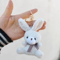 Detailed macro view of a white plush rabbit keychain with a brown plaid bow tie - Off White / Lobster Clasp Keychain