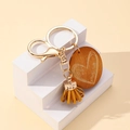 Détail du porte-clés en bois mama avec gravure de cœur et pompon en daim jaune - Marron