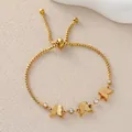 Elegante pulsera bolo dorada con mariposas mates y circonitas sobre fondo beige claro - Estilo Bolo Mariposa 3D Mate Con Diamante de Imitación (JY142-02)
